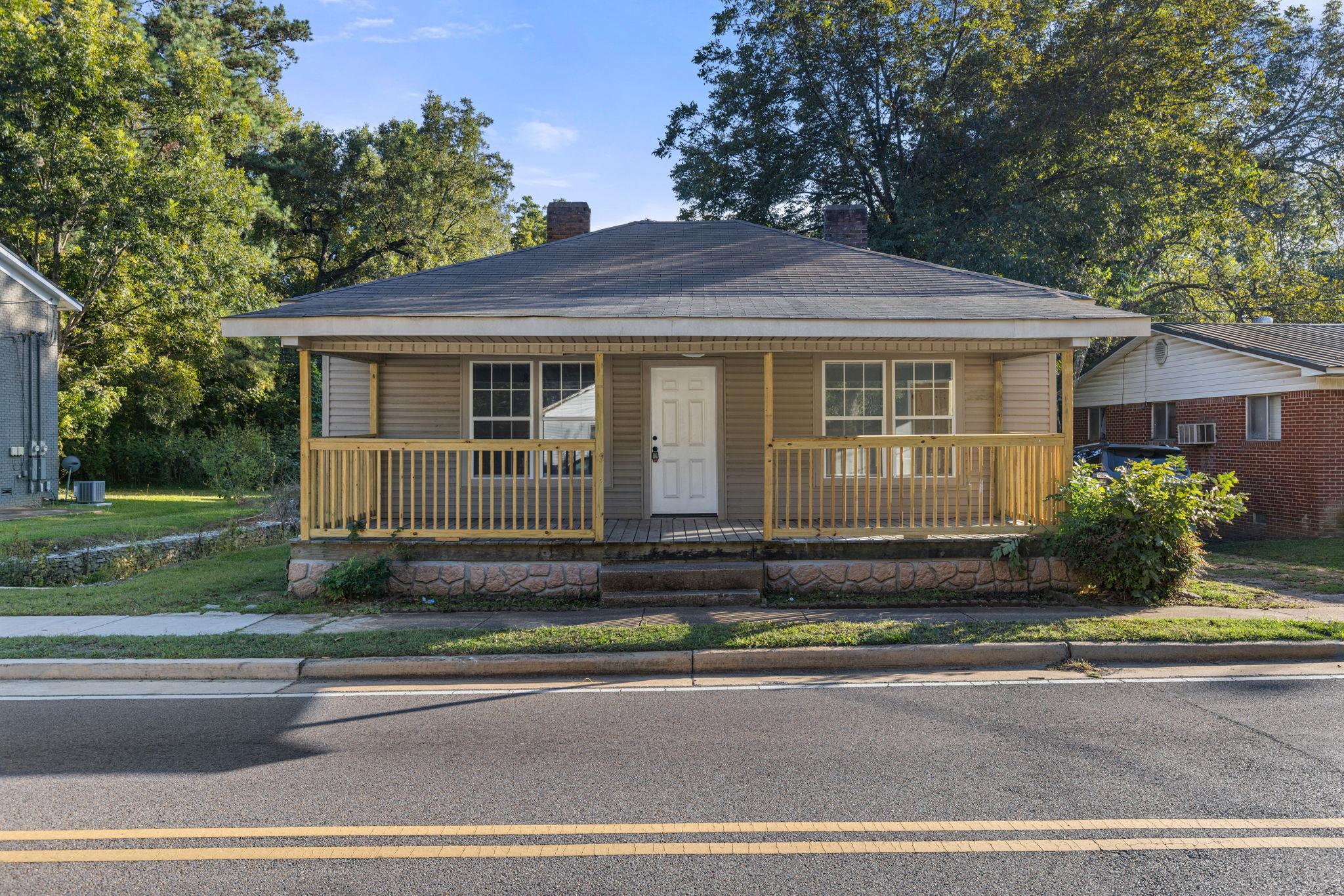 a view of a house with a small yard plants and large tree