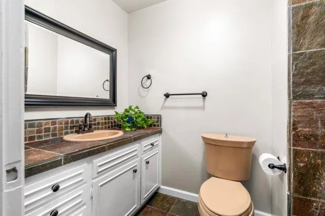a bathroom with a granite countertop toilet sink and mirror