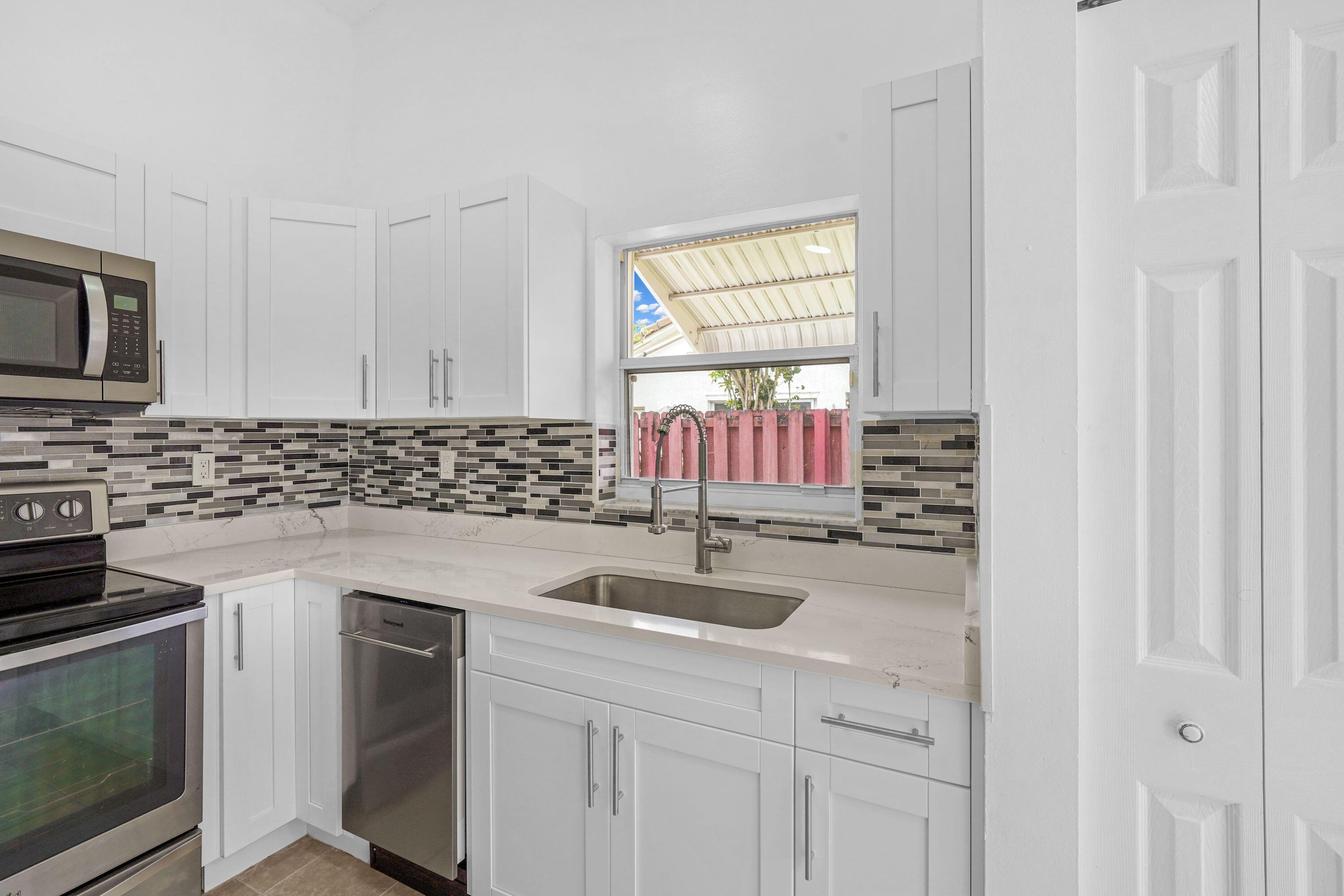 14142 Southwest 149th Court Miami, FL 33196 - Photo 14 of 48 a kitchen with granite countertop a sink stainless steel appliances a window and a counter top space