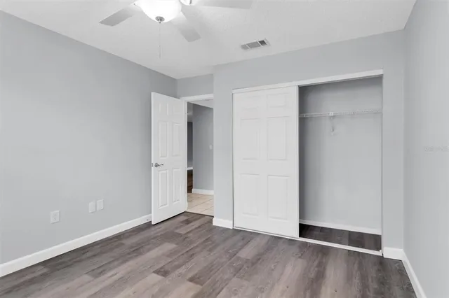 an empty room with wooden floor and a ceiling fan