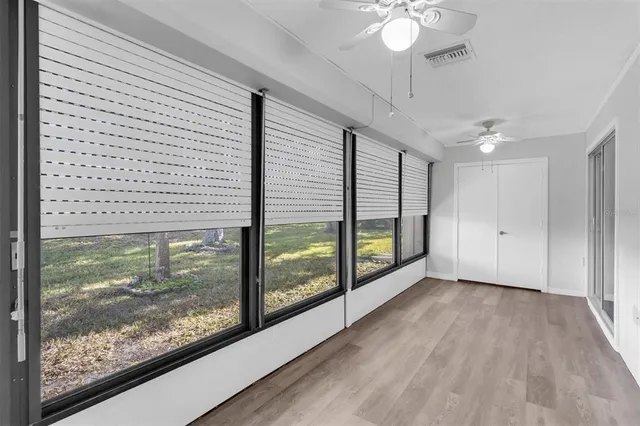 a view of a room with wooden floor fan and windows