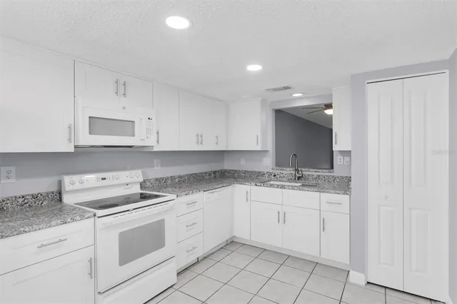 a kitchen with granite countertop white cabinets and white appliances