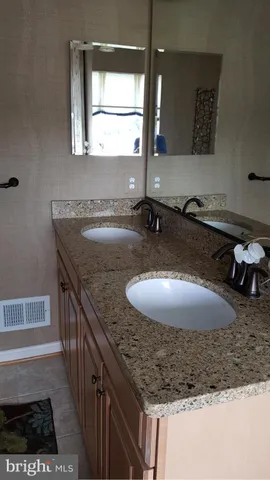 a bathroom with a granite countertop sink a mirror and a bathtub