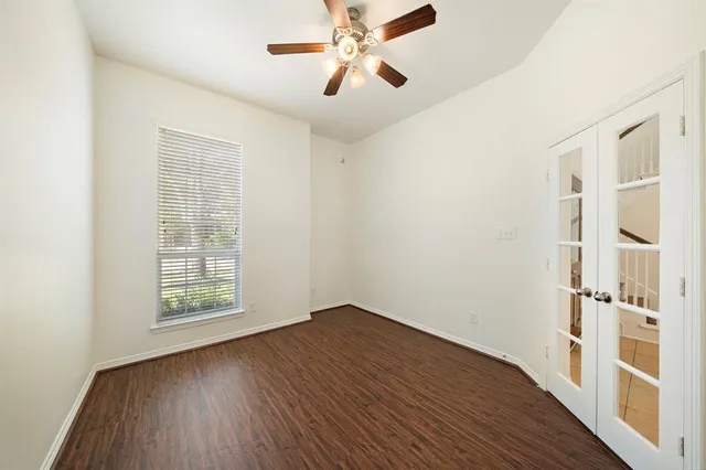 an empty room with wooden floor chandelier fan and windows
