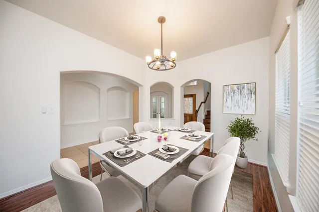 a dining room with wooden floor a chandelier a wooden table and chairs
