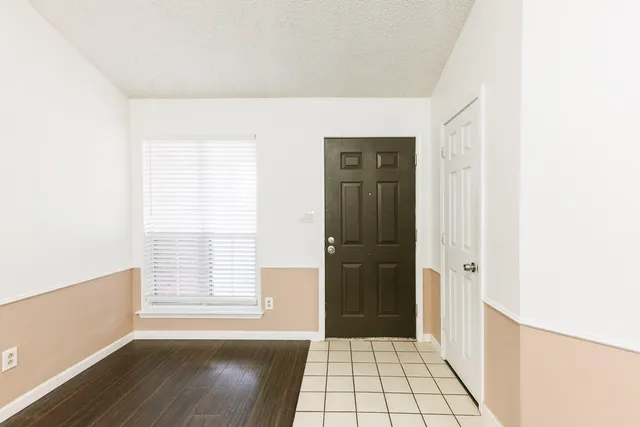 a view of an empty room with wooden floor and a fireplace