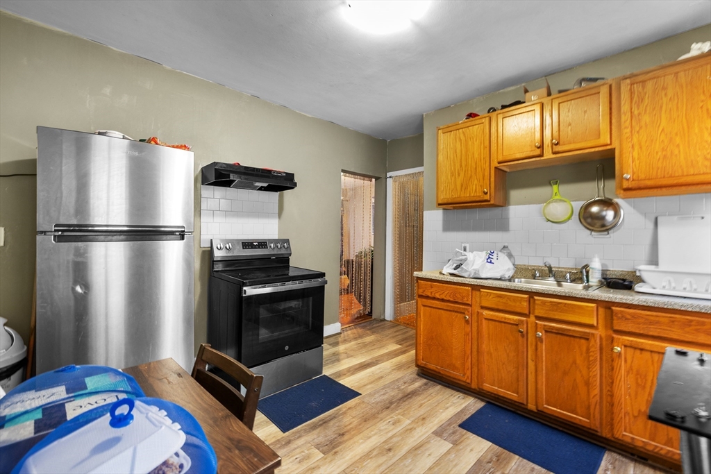 46 Theodore Street Boston, MA 02124 - Photo 18 of 24 a kitchen with stainless steel appliances granite countertop a refrigerator sink and wooden cabinets