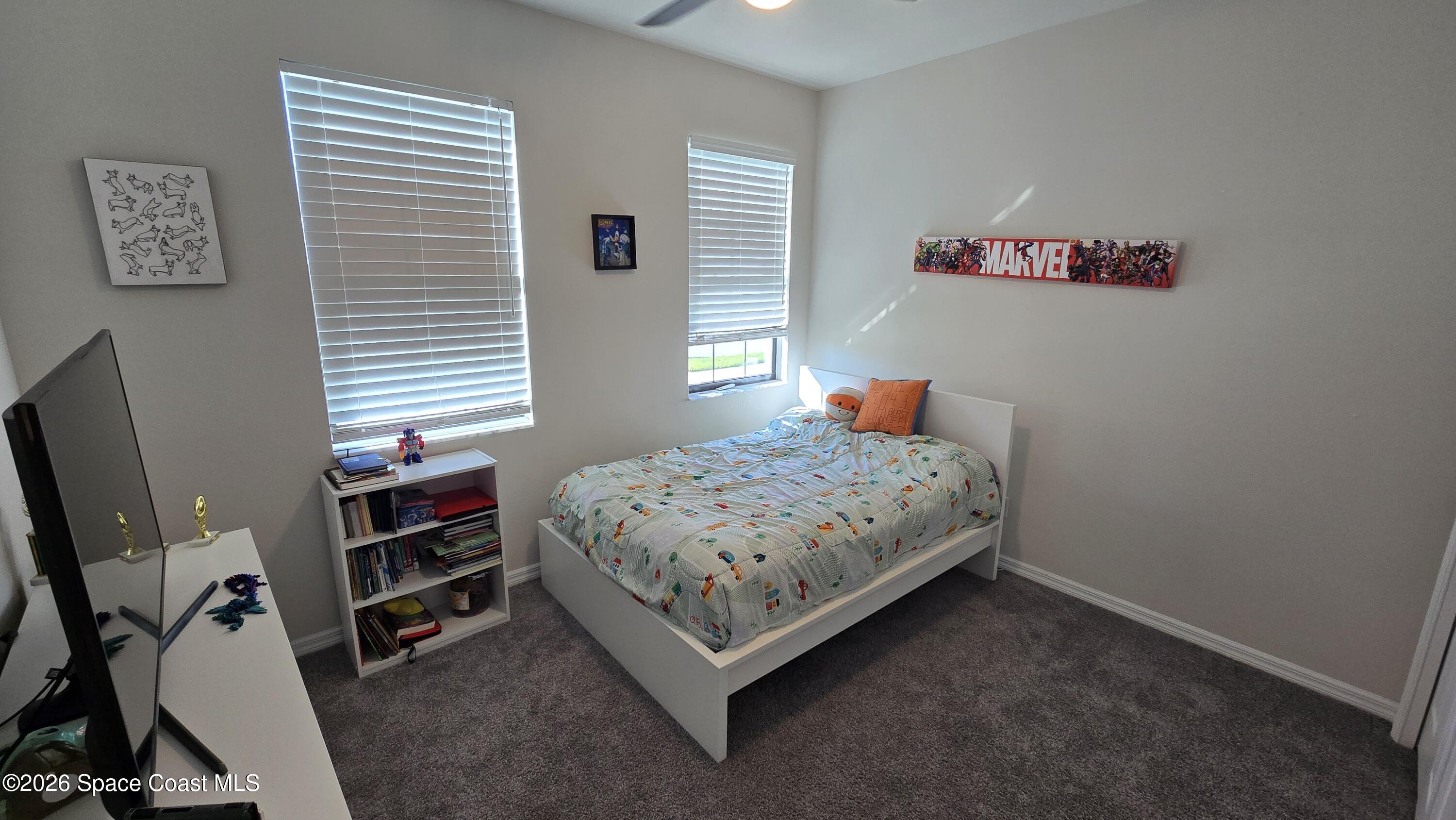 8137 Dobre Way Melbourne, FL 32940 - Photo 12 of 25 a bedroom with a bed and a flat tv screen on the dresser