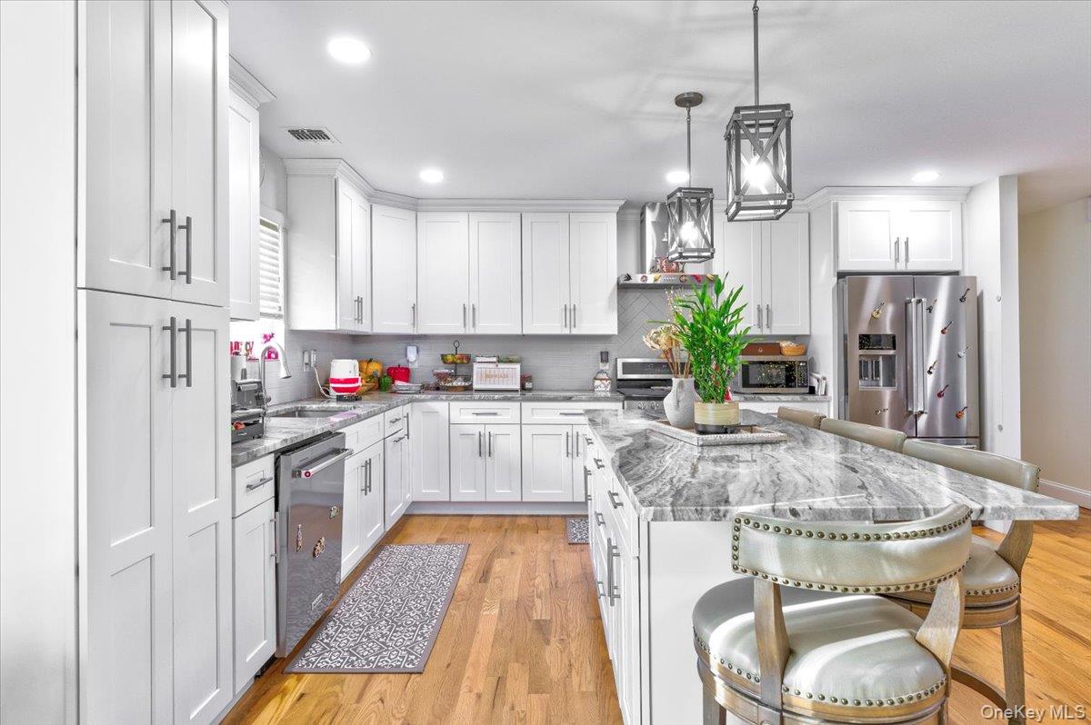 468 Granny Road Medford, NY 11763 - Photo 8 of 42 a kitchen with stainless steel appliances granite countertop a refrigerator a sink dishwasher a stove and white cabinets with wooden floor