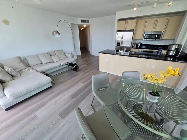 a living room with furniture kitchen view and a wooden floor