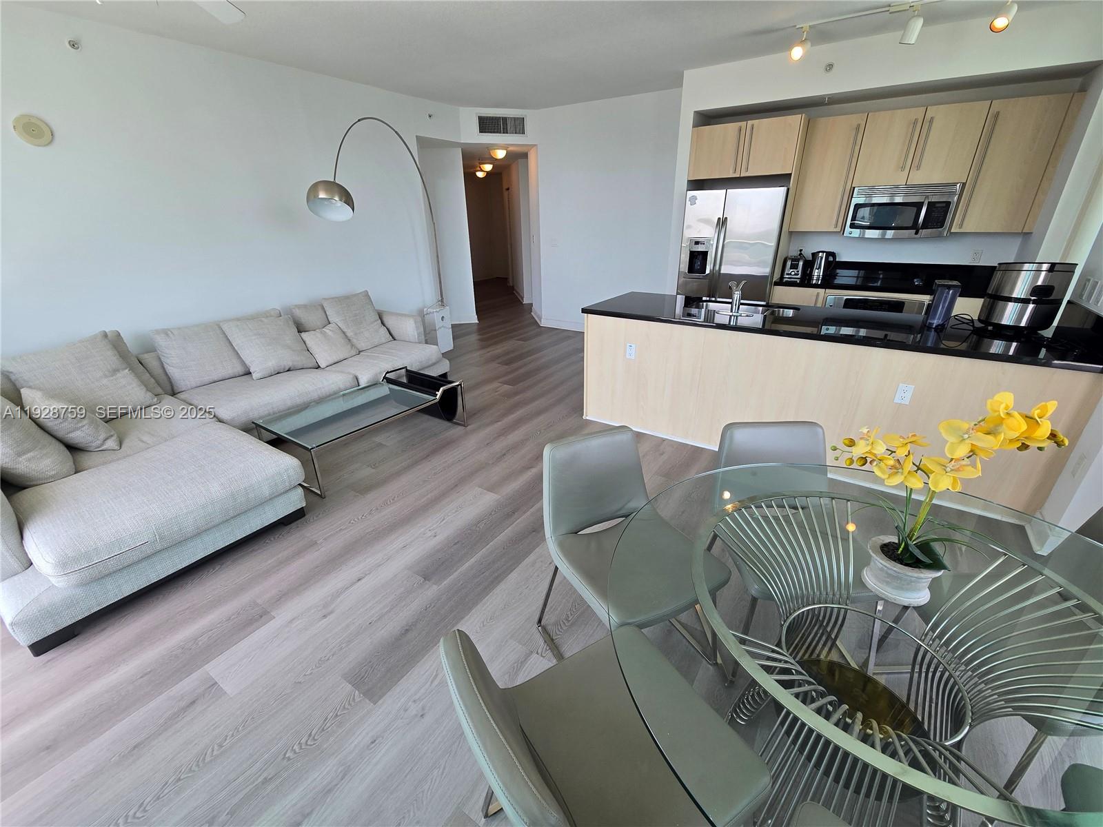 79 Southwest 12th Street, Unit 1701S Miami, FL 33130 - Photo 5 of 25 a living room with furniture kitchen view and a wooden floor