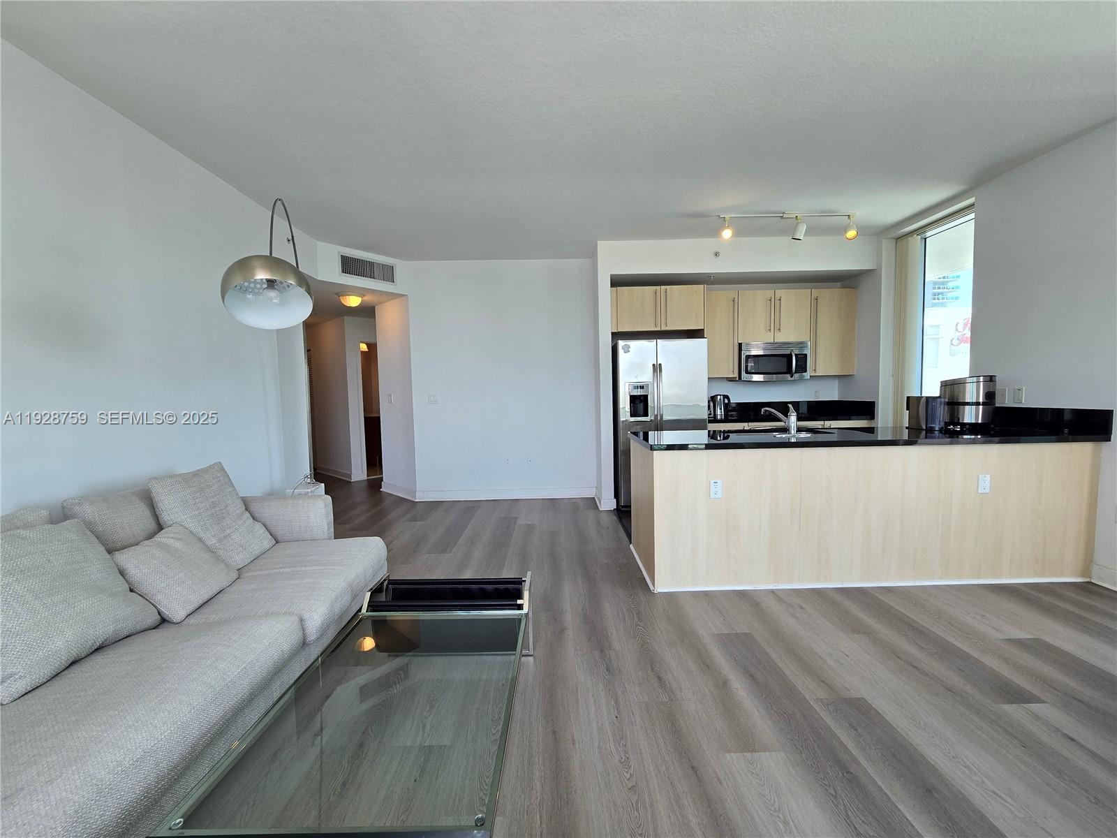 79 Southwest 12th Street, Unit 1701S Miami, FL 33130 - Photo 7 of 25 a living room with stainless steel appliances furniture a rug and a kitchen view