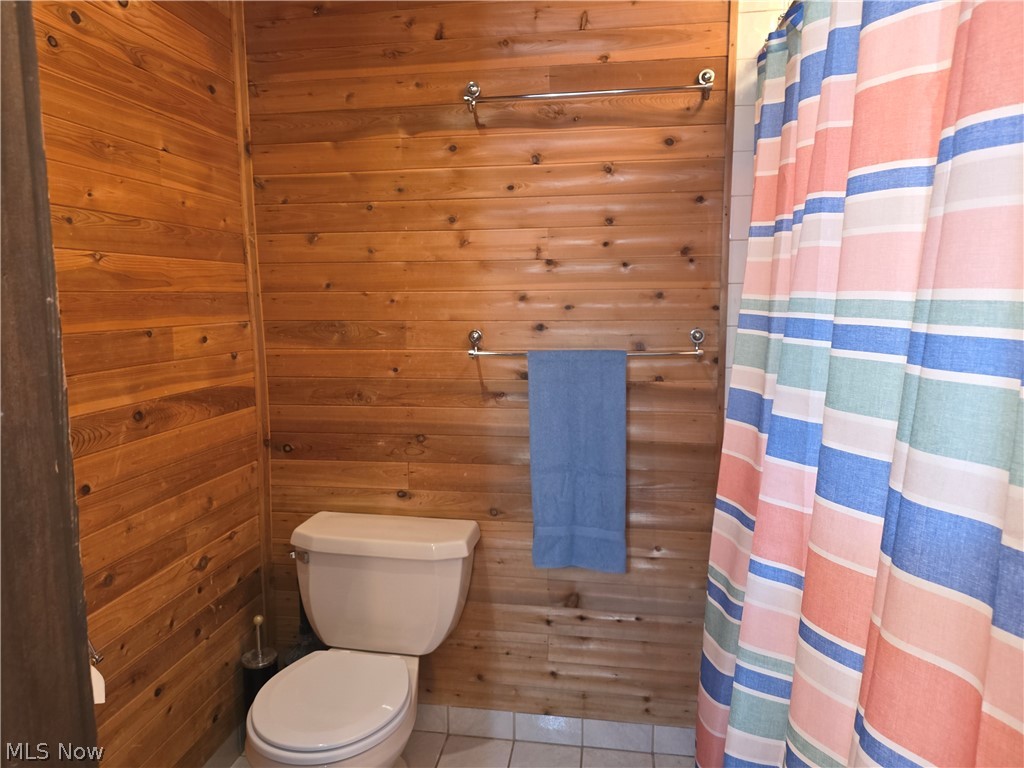 2868 Shade Road Akron, OH 44333 - Photo 8 of 49 Bathroom featuring natural wood plank walls, white floor tiling, and a standard toilet