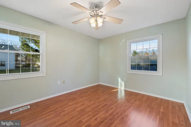 a view of an empty room with window and wooden floor