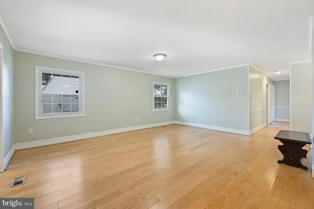 a view of an empty room with a window and a kitchen