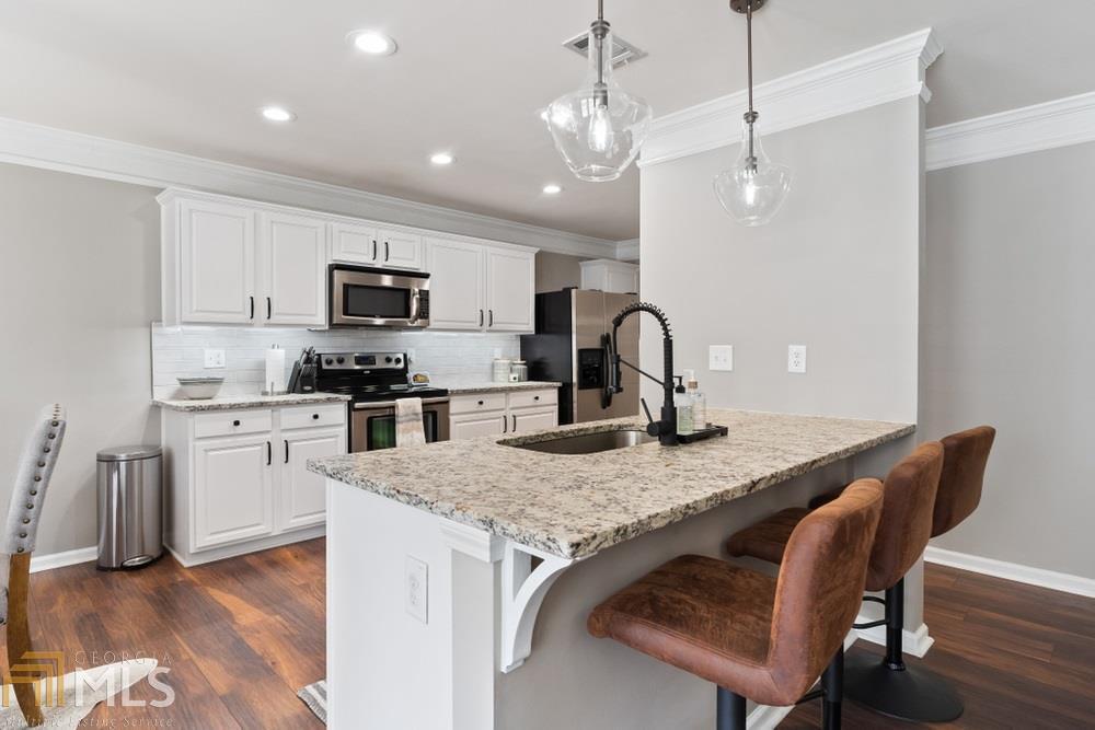 Designer touches everywhere in this perfect home! They've lowered the bar to create a perfect breakfast area and added granite, updated lighting and backsplash.
