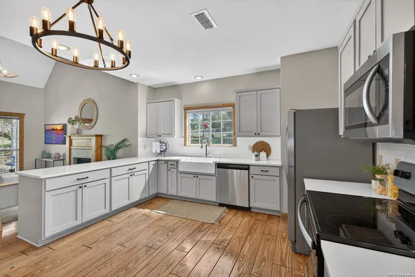 a kitchen with a sink dishwasher a dining table and chairs with wooden floor