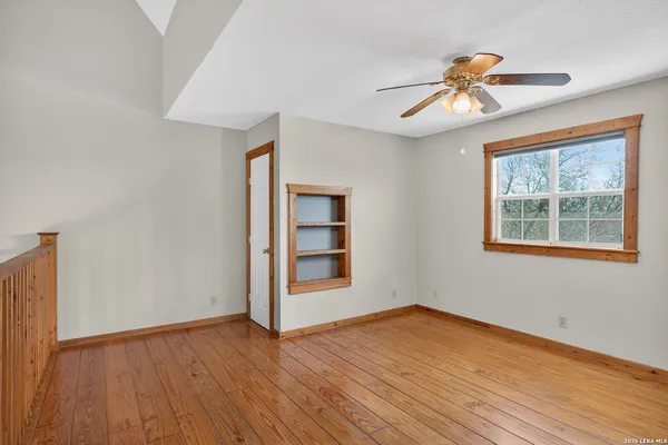 a view of empty room with wooden floor and fan