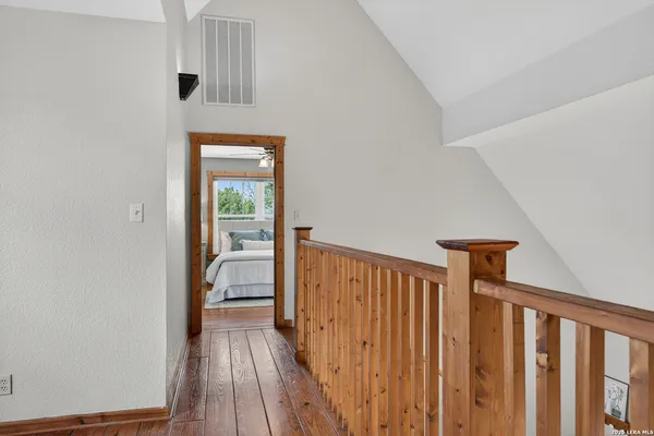 a view of a hallway with wooden floor and a bathroom