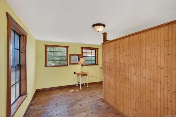 a view of an empty room with a window and wooden floor