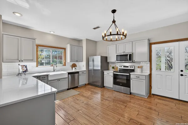 a kitchen with stainless steel appliances a stove a sink dishwasher a refrigerator and a dining table with wooden floor