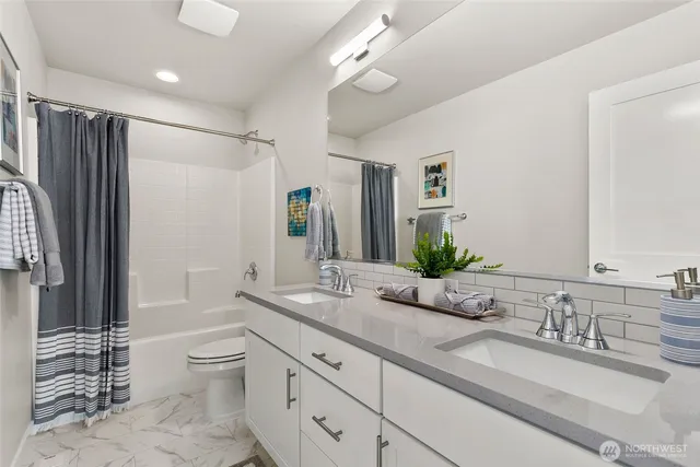 a bathroom with a granite countertop sink mirror vanity bathtub and a toilet