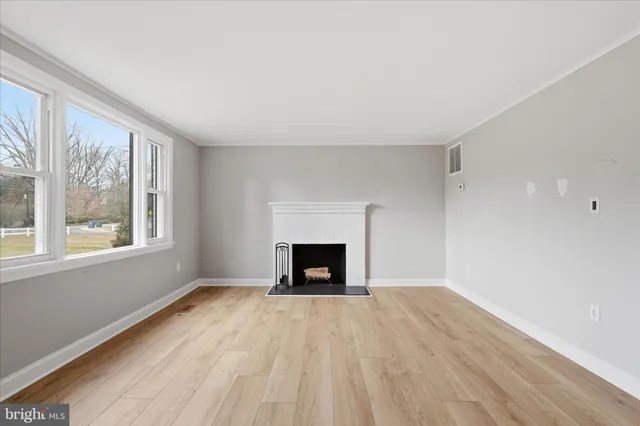 wooden floor fireplace and windows in an empty room