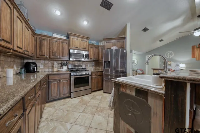 a kitchen with stainless steel appliances granite countertop a sink stove and refrigerator