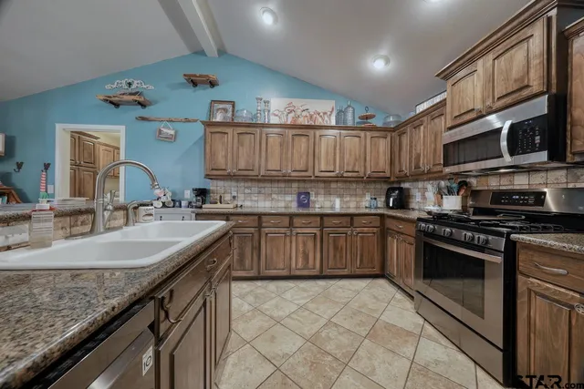 a kitchen with stainless steel appliances granite countertop a sink stove and cabinets