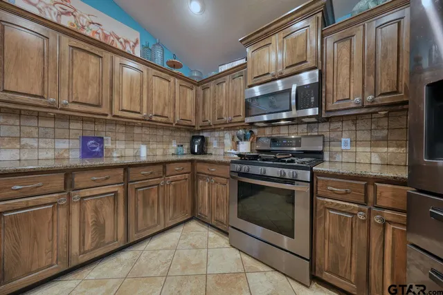 a kitchen with stainless steel appliances granite countertop a stove microwave and cabinets