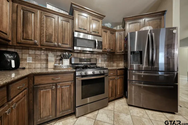 a kitchen with stainless steel appliances granite countertop a refrigerator stove and sink