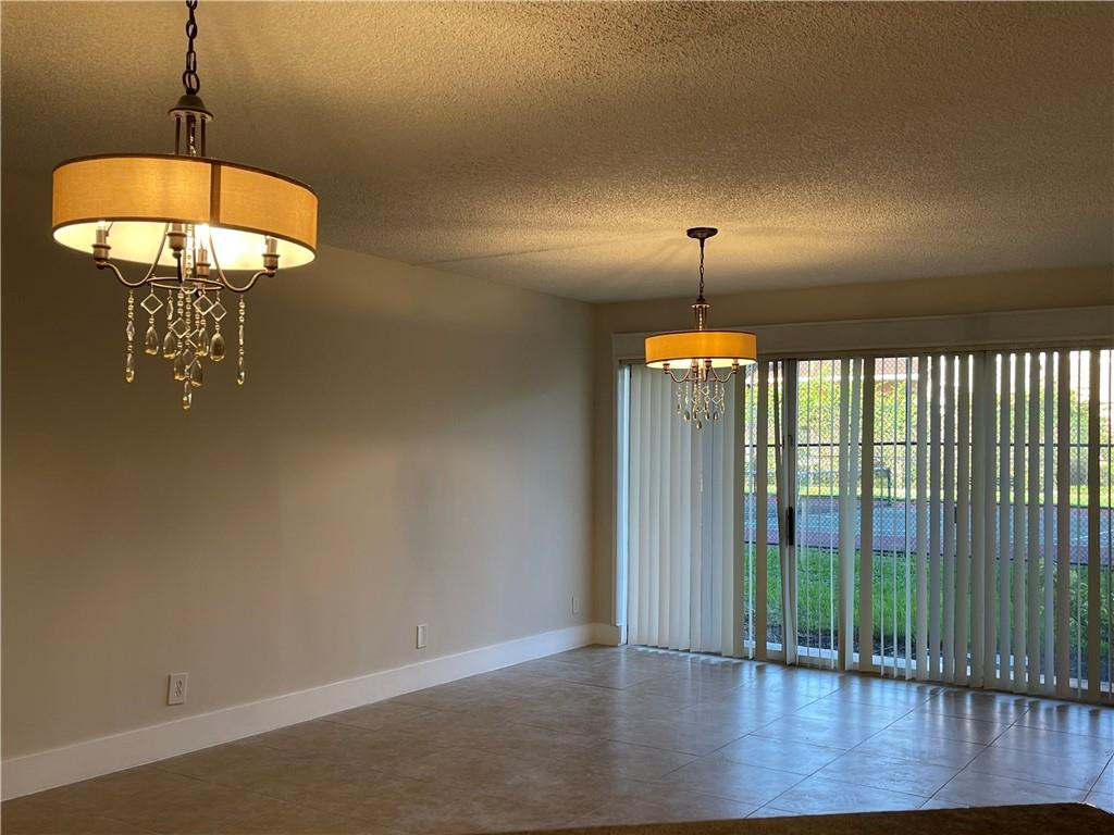 8801 Wiles Road, Unit 108 Coral Springs, FL 33067 - Photo 3 of 22 wooden floor in an empty room with a chandelier