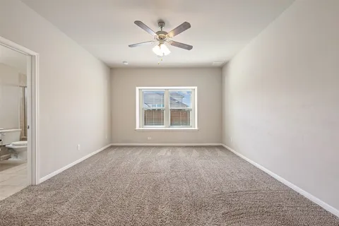 an empty room with chandelier fan and windows