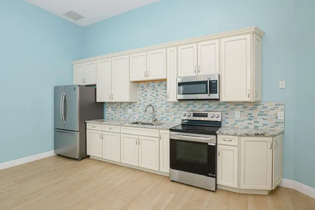 a kitchen with stainless steel appliances granite countertop a stove top oven microwave and refrigerator