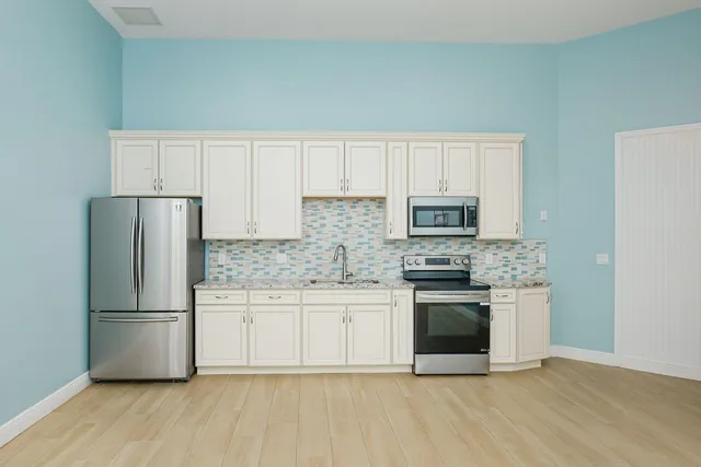 a kitchen with granite countertop a refrigerator stove and microwave with wooden floor