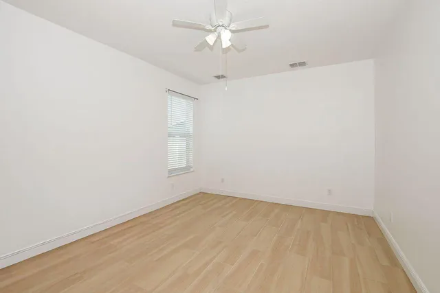 an empty room with a window and a ceiling fan
