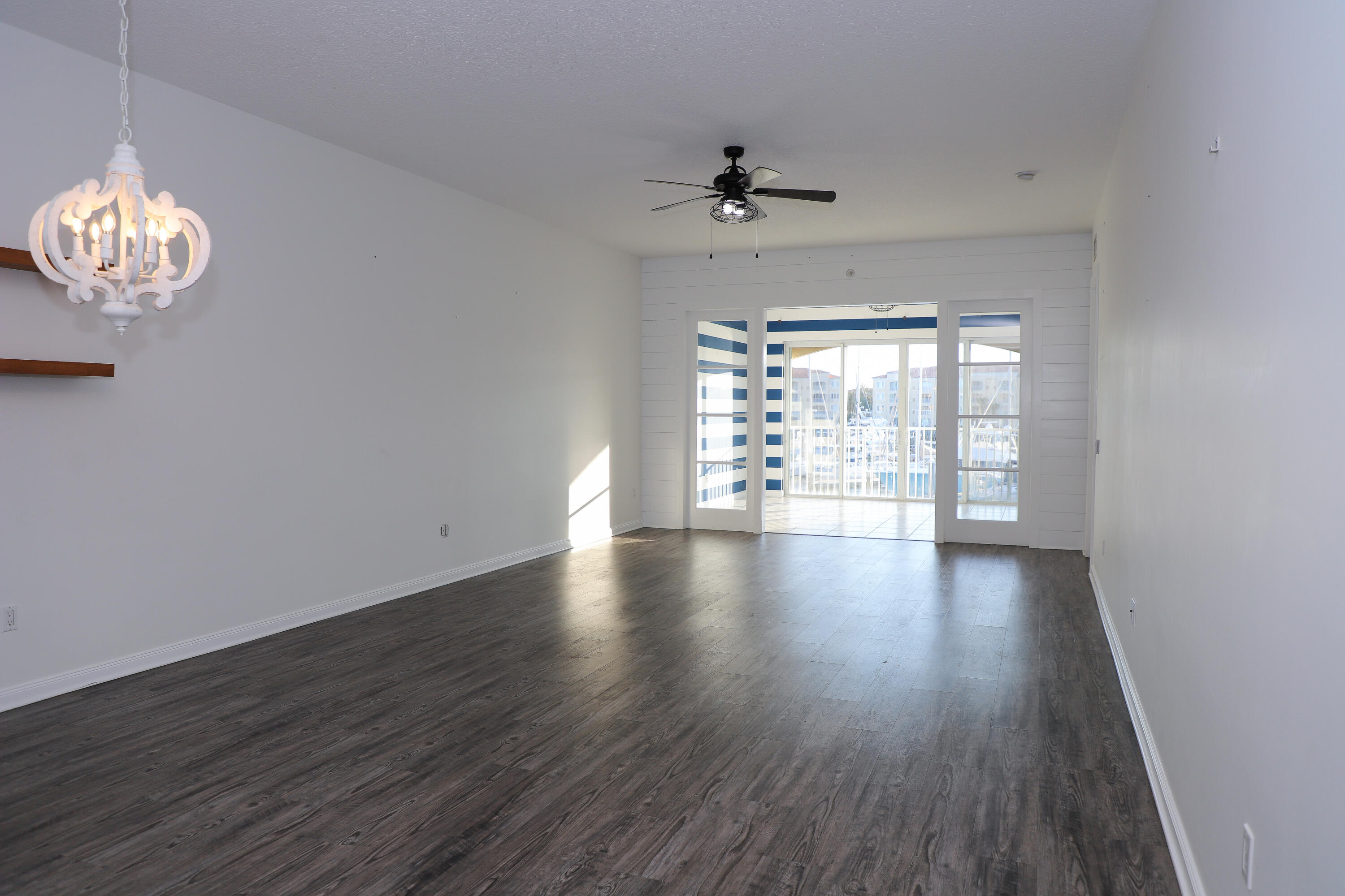 10 Harbour Isle Drive East, Unit 206 Fort Pierce, FL 34949 - Photo 3 of 12 an empty room with wooden floor chandelier fan and windows