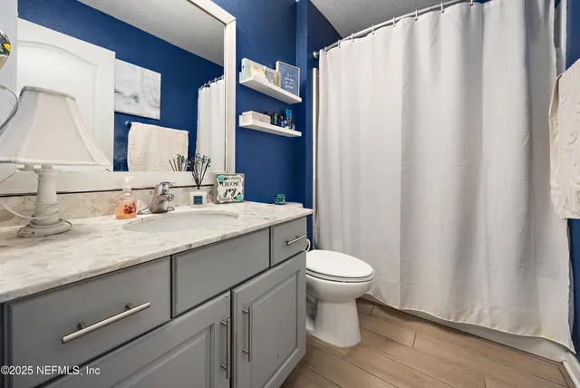 a bathroom with a granite countertop sink toilet and mirror