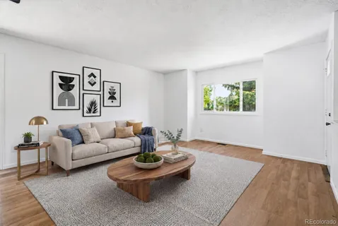 a living room with couches and a potted plant next to a window