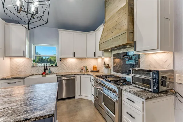 a kitchen with kitchen island granite countertop a sink cabinets stainless steel appliances and a counter top