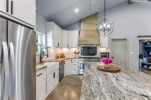 a kitchen with stainless steel appliances kitchen island granite countertop a refrigerator and a stove