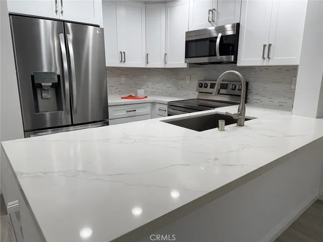 a kitchen with stainless steel appliances a refrigerator a sink a stove a microwave and cabinets