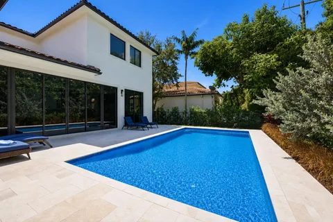 a view of swimming pool with seating space and trees in the background