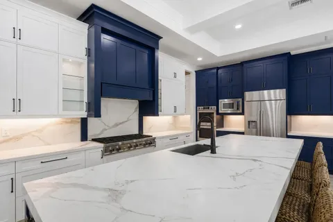 a large white kitchen with wooden floors and stainless steel appliances