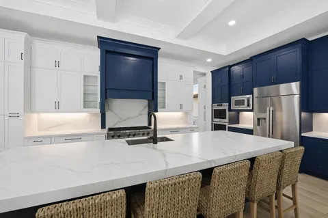 a kitchen with kitchen island granite countertop wooden cabinets a stove a sink and a refrigerator