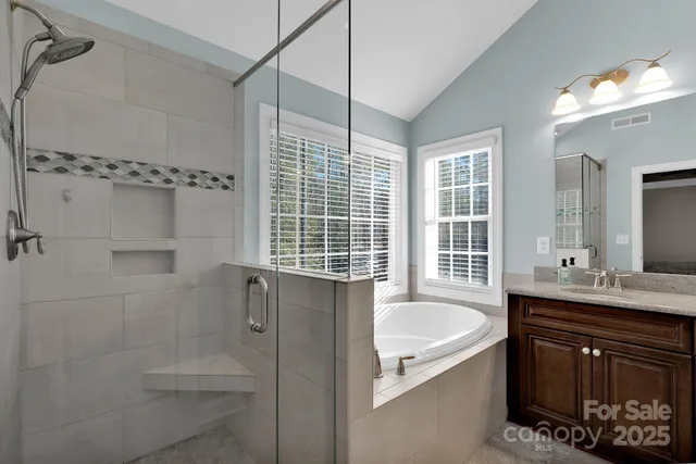 a bathroom with a tub a sink a window and a shower