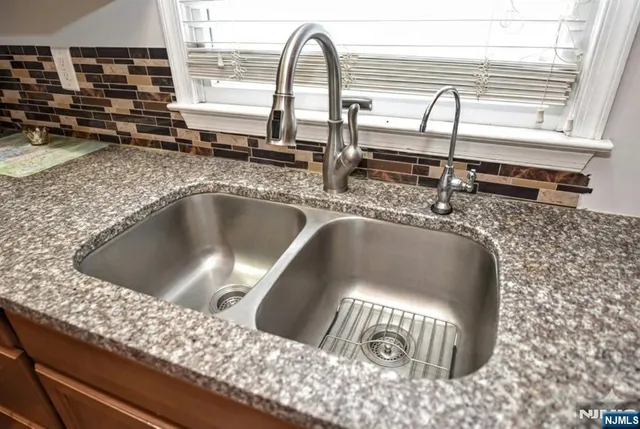a kitchen with a granite countertop sink and mirror