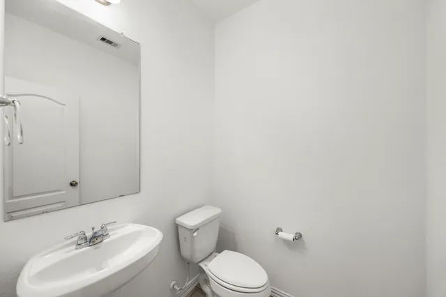 a view of an empty room with wooden floor and a kitchen