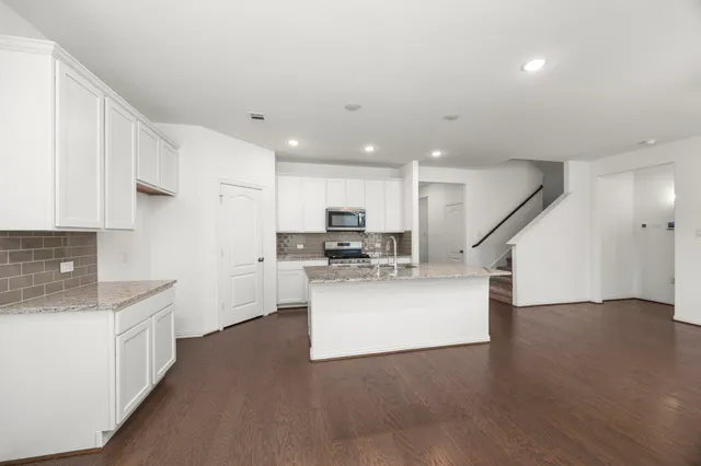a kitchen with granite countertop a sink a counter top space stainless steel appliances and cabinets