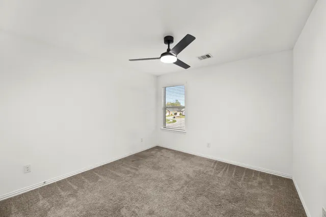 an empty room with a window and a fan